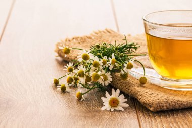 Cam bardak yeşil çay ahşap arka plan üzerinde beyaz papatya çiçeği ile