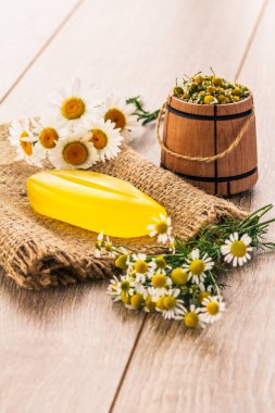 Sarı soap çul kokulu taze chamomiles ve arka plan üzerinde küçük ahşap varil üzerinde. Doğal kozmetik ve spa ürünleri