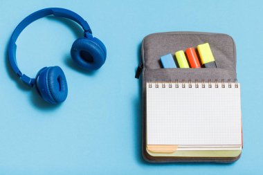 Kulaklıklar, kalemler ve marker mavi zemin üzerine açık egzersiz kitap renk ile çanta-kalem duruma hissettim. Üstten görünüm kopya alanı ile. Geri okul kavramı. Okul malzemeleri.