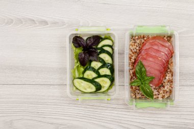 Plastik yemek kapları taze salatalık ve salata, haşlanmış Buğday lapası ve gri ahşap arka plan üzerinde et dilimleri ile hazırlayın. Kopya alanı ile üstten görünüm