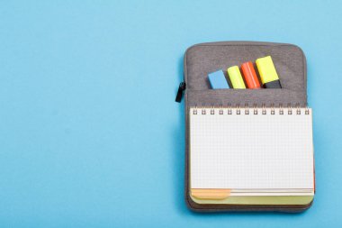 Kulaklıklar, kalemler ve marker mavi zemin üzerine açık egzersiz kitap renk ile çanta-kalem duruma hissettim. Üstten görünüm kopya alanı ile. Geri okul kavramı. Okul malzemeleri.