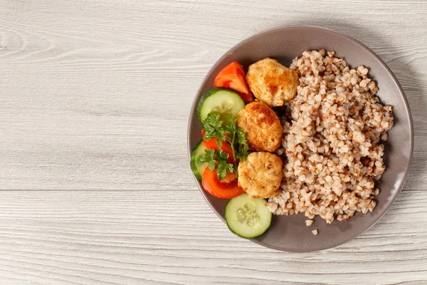 Plaka ile buğday, kızarmış et pirzola, adet taze salatalık ve domates taze maydanoz dalı ile dekore edilmiştir. Kopya alanı ile üstten görünüm