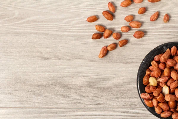 Kopya alanı gri ahşap zemin üzerine siyah porselen kapta ve yanındaki fıstık üstten görünüm