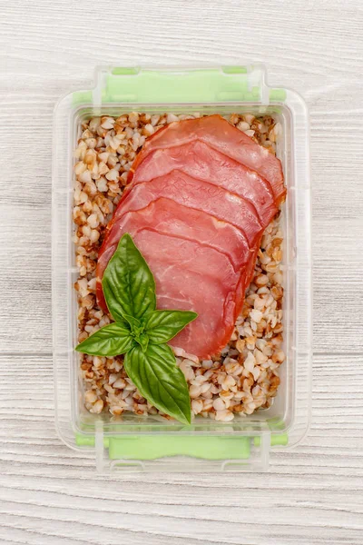Plastik yemek hazırlayın haşlanmış Buğday lapası ile konteyner ve et dilimleri. Üstten görünüm
