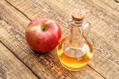 Cam şişe mantarı ve eski ahşap kurullarında taze kırmızı elma ile elma sirkesi. Üstten görünüm