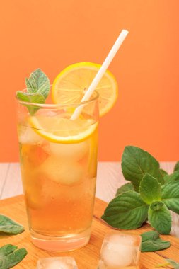 Nane ile dekore edilmiş, buz ve limon dilimleri ile yaz limonata ferahlatıcı soğuk bir yüksek cam kesme tahtası üzerinde bırakır.