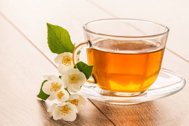 Cam bardak yeşil çay ahşap arka plan üzerinde beyaz yasemin çiçekleri ile