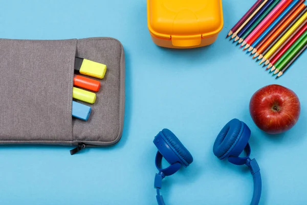 Okul malzemeleri. Çanta-kalem çalışmasıyla renk kalemler ve marker, beslenme çantası, renkli kalemler, elma ve mavi arka plan kulaklıktan hissettim. Üstten görünüm. Geri okul kavramı
