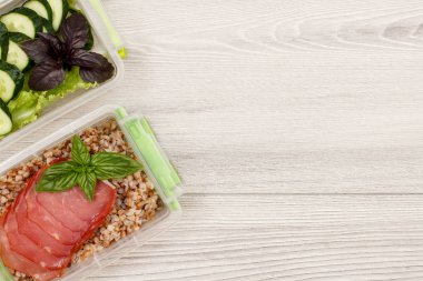 Plastik yemek kapları ile haşlanmış Buğday lapası ve dilim et, taze salatalık ve gri ahşap zemin üzerine salata hazırlayın. Kopya alanı ile üstten görünüm