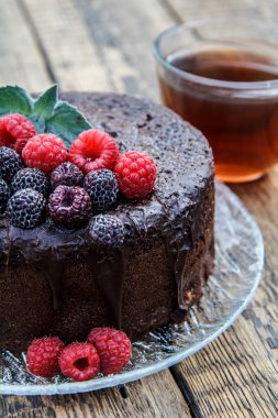 Ev yapımı nane yaprakları ile siyah çikolatalı kek dekore edilmiş ve cam üzerinde kırmızı ahududu çay ahşap kurullarında ile plakası