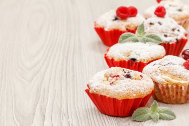 Ev yapımı kekler pudra şekeri ve taze ahududu ahşap kesme tahtası üzerine serpilir. Kopya alanı