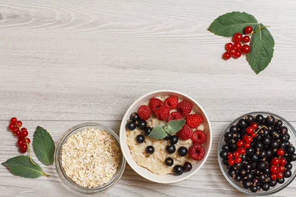 Yulaf lapası frenk üzümü çilek ve ahududu, nane yaprakları ile dekore edilmiş porselen kase cam çilek yulaf gevreği ve kuş üzümü ile kase. Kopya alanı ile üstten görünüm