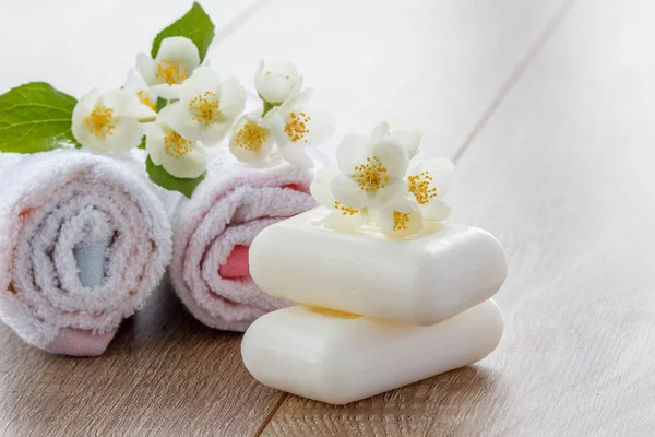 Beyaz havlu ve sabun banyo yordamları için ahşap kurullarında Yasemin çiçekleri ile süslenmiş. Spa ürünleri ve aksesuarları