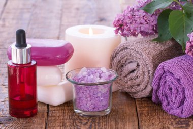 Aromatik yağ, sabun, mum, deniz tuzu, Lila çiçek ve havlu banyo yordamlar ahşap kurullarında için kase yanan kırmızı şişe. Spa ürünleri ve aksesuarları