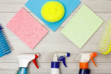 Deterjan, şişe renk mikrofiber bezler, sentetik sünger ve gri ahşap arka plan üzerinde temizlik için fırçalar. Araçları ve ekipmanları temizlik seti