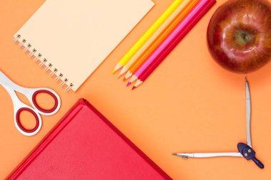 Kitap, makas, defter, renkli kalemler, elma ve pusula pembe bir arka plan üzerinde. Üstten görünüm. Geri okul kavramı. Okul malzemeleri. Pastel renkler