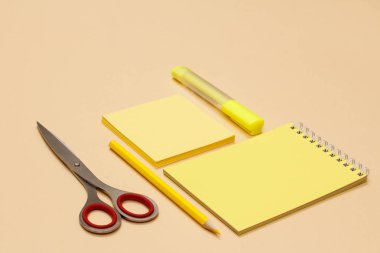 Makas, kalem, defter, not kağıdı ve sarı keçeli kalem bej renkli arka plan üzerinde. Geri okul kavramı. Okul malzemeleri. Pastel renkler