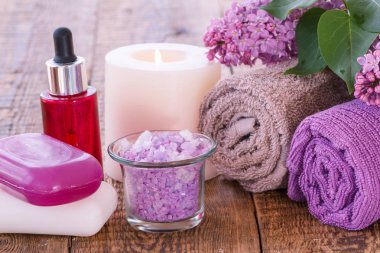 Aromatik yağ, mum, deniz tuzu, Lila çiçek ve havlu banyo yordamlar ahşap kurullarında için kase yanma ile sabun, kırmızı şişe. Spa ürünleri ve aksesuarları