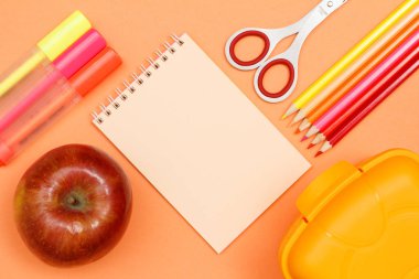 Apple, kalem, defter, makas, renkli kalemler ve beslenme çantası pembe bir arka plan üzerinde hissetti. Üstten görünüm kopya alanı ile. Geri okul kavramı. Okul malzemeleri. Pastel renkler