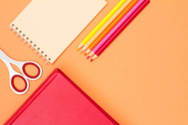 Pembe bir arka plan üzerinde kitap, makas, defter ve renkli kalemler. Üstten görünüm kopya alanı ile. Geri okul kavramı. Okul malzemeleri. Pastel renkler