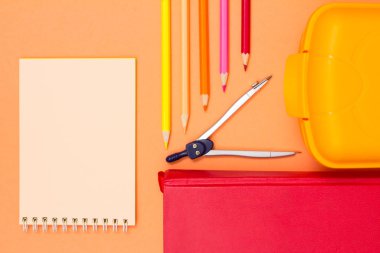 Defter, kitap, pusula, renkli kalemler ve beslenme çantası pembe bir arka plan üzerinde. Üstten görünüm kopya alanı ile. Geri okul kavramı. Okul malzemeleri. Pastel renkler