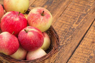 Kırmızı elma hasır sepet ve Bahçe eldiven ile eski ahşap kurullarında. Kopya alanı ile üstten görünüm