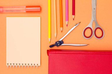 Defter, keçeli kalem, renkli kalemler, pusula, kitap ve pembe bir arka plan için makaslar. Üstten görünüm kopya alanı ile. Geri okul kavramı. Okul malzemeleri. Pastel renkler