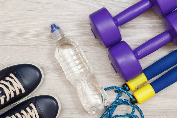 Different tools for fitness with bottle of water in room or gym on grey floor