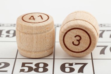 İki ahşap varil numaraları ve beyaz bir arka plan bir loto oyun kartı. Yakın çekim görünümü