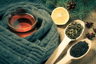 Çay yün atkı, dilimlenmiş limon, yeşil ve siyah çay yaprakları ile tahta kaşıklar, doğal köknar ağacı dalları koni ve anasonu Sim Tarih ile sarılmış. Renk efekti tonlama.