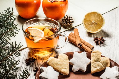 Fincan çay dilim limon, gingerbread çerezleri yıldız ve kalp ile şekil, doğal köknar ağacı dalları ile koni ve tarçın, anasonu ahşap kurullarında. Renk efekti tonlama.