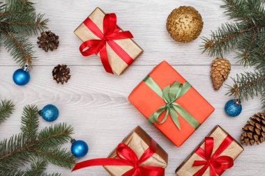 Noel dekorasyonu. Hediye kutuları, koni ve Noel oyuncaklar gri ahşap kurullarında köknar ağacı dalları. Üstten görünüm. Noel tebrik kartı kavramı.