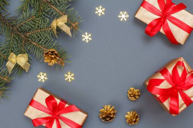 Noel dekorasyonu. Hediye kutuları, gri arka plan üzerinde koniler ile doğal köknar ağacı dalları. Üstten görünüm. Noel tebrik kartı kavramı.