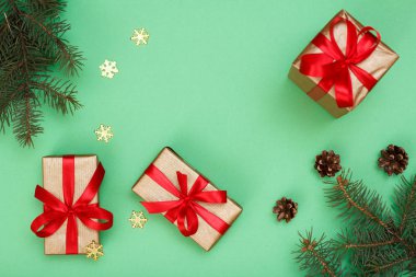 Noel dekorasyonu. Hediye kutuları, koni ve yeşil zemin üzerine dekoratif kar tanesi köknar ağacı dalları. Üstten görünüm. Noel tebrik kartı kavramı.