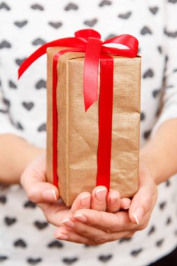 Bir hediye kutusu tutarak Wooman onun elinde kırmızı kurdele ile bağlanmış. Alan, seçici odak üstünde belgili tanımlık kutu sığ derinliği. Sevgililer günü veya Doğum günü hediye verme kavramı.