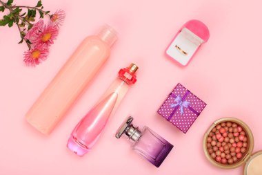 Hediye kutusu, şişe parfüm, şampuan, toz ve kutusunda pembe bir arka plan üzerinde altın yüzük. Kadın kozmetik ve aksesuarları. Üstten görünüm.