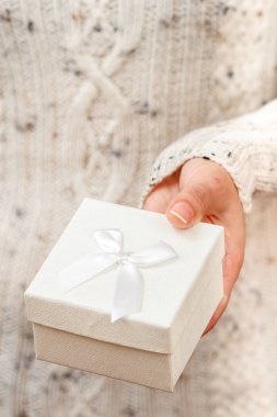 Elinde hediye kutusu tutan bir kadın. Sığ alan derinliği, seçmeli olarak kutuya odaklan. Tatilde ya da doğum gününde hediye verme kavramı.