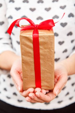 Bir hediye kutusu tutan kadın ellerinde kırmızı kurdele ile bağlanmış. Alan, seçici odak üstünde belgili tanımlık kutu sığ derinliği. Sevgililer günü veya Doğum günü hediye verme kavramı.