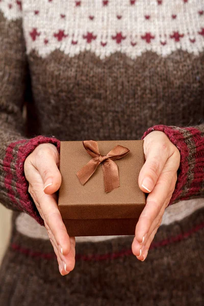 Woman holding a gift box in her hands. Shallow depth of field, Selective focus on the box. Concept of giving a gift on holiday or birthday.