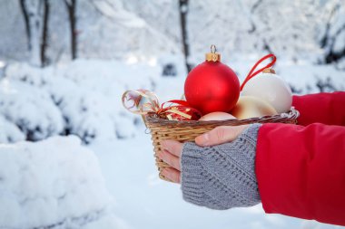 Kadın bir hasır sepet Noel topları ile karla kaplı ağaçlar ile kış şehir parkı içinde tutuyor. Noel ve yeni yıl kompozisyon.