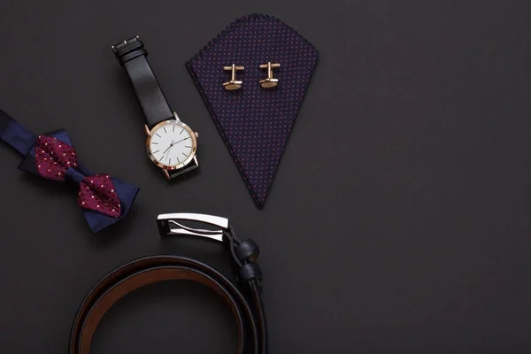 Metal toka, papyon, seyretmek ile bir siyah deri kayışı ve siyah arka plan üzerine kol düğmeleri ile mendil ile deri kemer. Erkekler için aksesuarlar. Üstten görünüm.