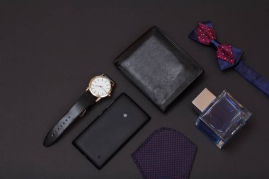 Deri çanta, siyah deri kayışı, Köln erkek, papyon, cep telefonu ve siyah arka plan üzerine mendil için saatle. Erkekler için aksesuarlar. Üstten görünüm.