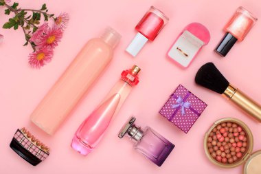 Hediye kutusu, şişe parfüm ve şampuan, hairgrip, altın yüzük kutusu, tırnak cilası, toz pembe bir arka plan üzerinde fırça ile. Kadın kozmetik ve aksesuarları. Üstten görünüm.