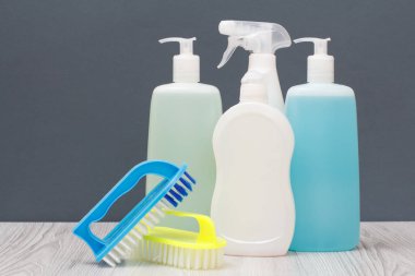 Plastik şişe bulaşık deterjanı, cam ve döşeme temizleyici, mikrodalga fırın ve soba, deterjan fırçalar üzerinde arka plan gri. Yıkama ve Temizleme kavramı.