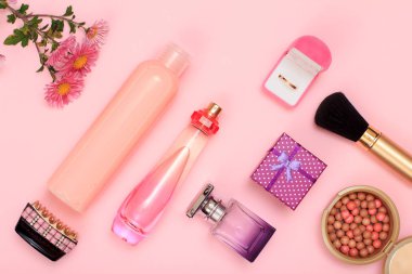 Hediye kutusu, şişe parfüm ve şampuan, saç kavrama, altın yüzük bir kutu içinde toz pembe bir arka plan üzerinde fırça ile. Kadın kozmetik ve aksesuarları. Üstten görünüm.