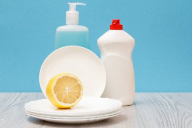 Döşeme Temizleyici, bulaşık deterjanı, cam ve plastik şişe temiz tabak ve mavi zemin üzerine limon. Yıkama ve Temizleme kavramı.