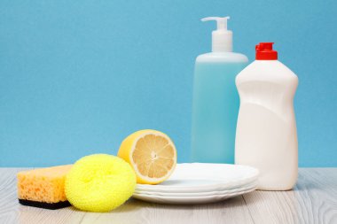 Döşeme Temizleyici, bulaşık deterjanı, cam ve plastik şişe temiz tabak, limon ve mavi zemin üzerine sünger. Yıkama ve Temizleme kavramı.