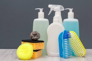 Plastik şişe bulaşık deterjanı, cam ve döşeme temizleyici, mikrodalga fırın ve soba, fırça ve sünger gri arka plan üzerinde deterjan. Yıkama ve Temizleme kavramı.