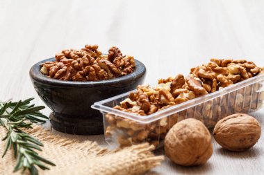 Soyulmuş ve soyulmamış ceviz taş kase ve Plastik Konteyner ile yas ve biberiye ahşap arka plan üzerinde. Yararlı besleyici protein ürün. Sığ derinlik-in tarla.