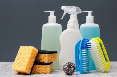 Plastik şişe bulaşık deterjanı, cam ve döşeme temizleyici, mikrodalga fırın ve soba, fırça ve sünger gri arka plan üzerinde deterjan. Yıkama ve Temizleme kavramı.